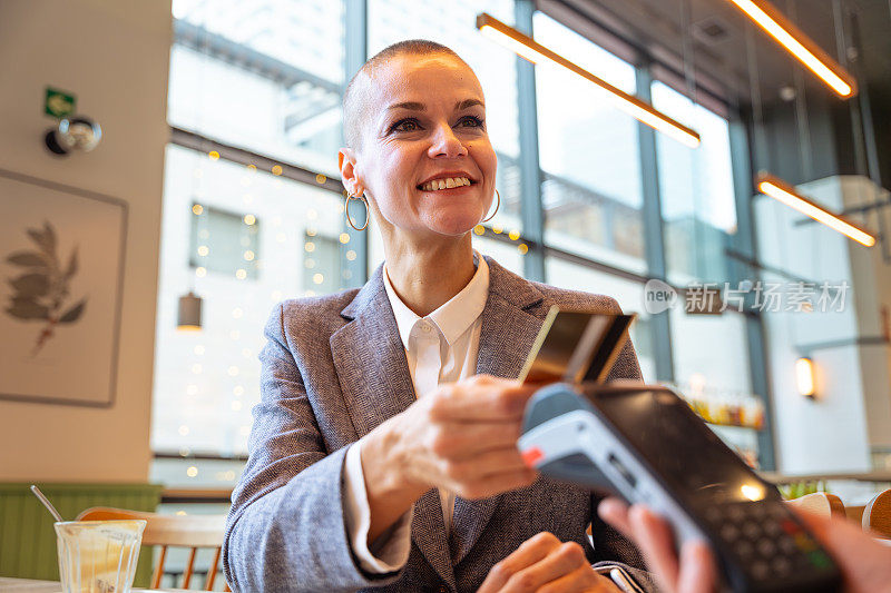 Smiling customer paying with contactless credit card in a restaurant.